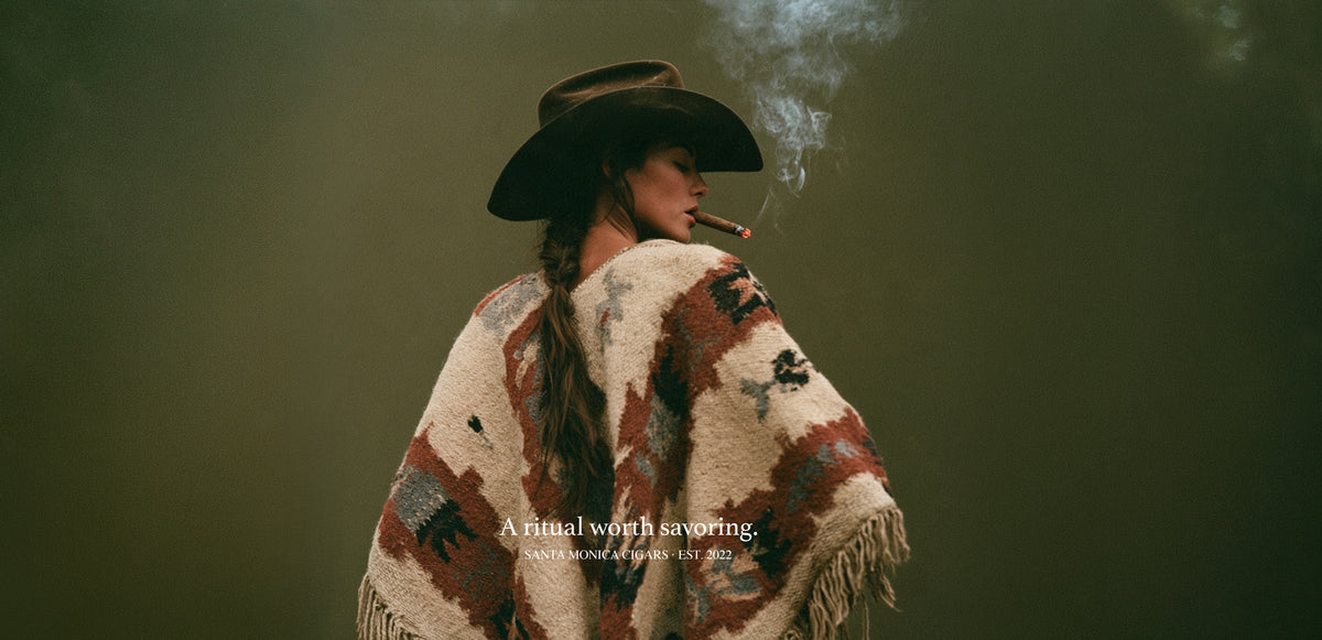 Santa Monica Cigar Banner Woman Smoking a Cigar In dark brown cowboy hat and patterned poncho.